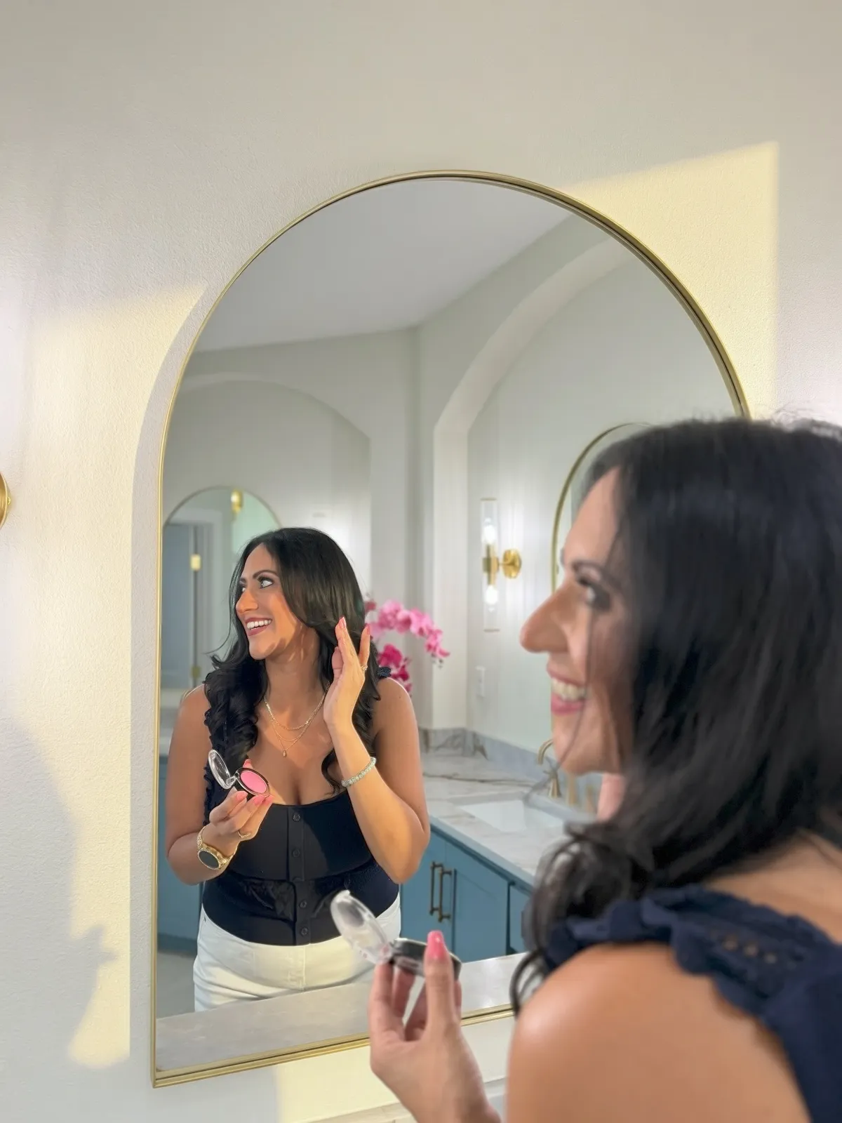 An editorial getting-ready moment shot in a sunlit arched mirror